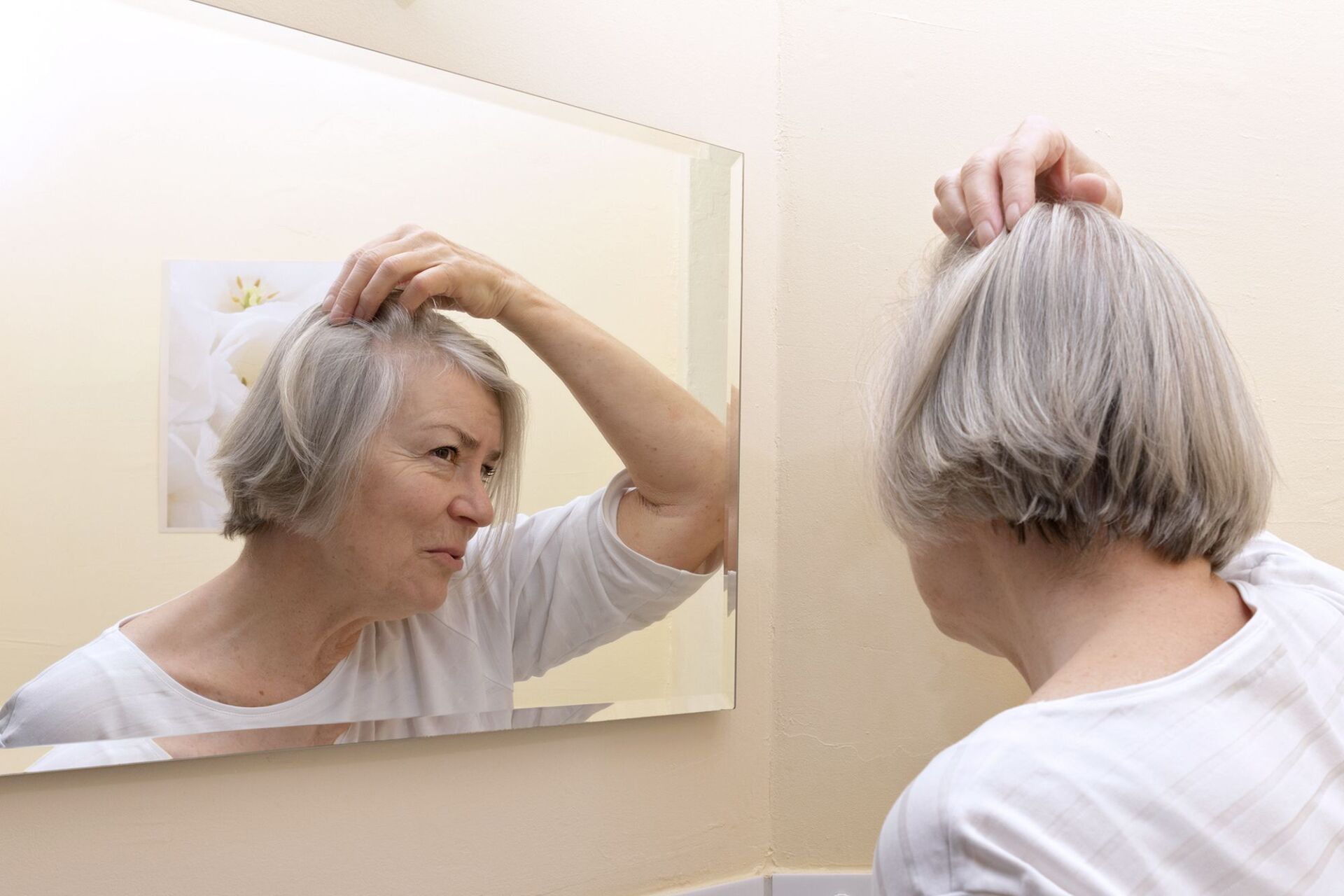 Frau mit Haarausfall vor dem Spiegel